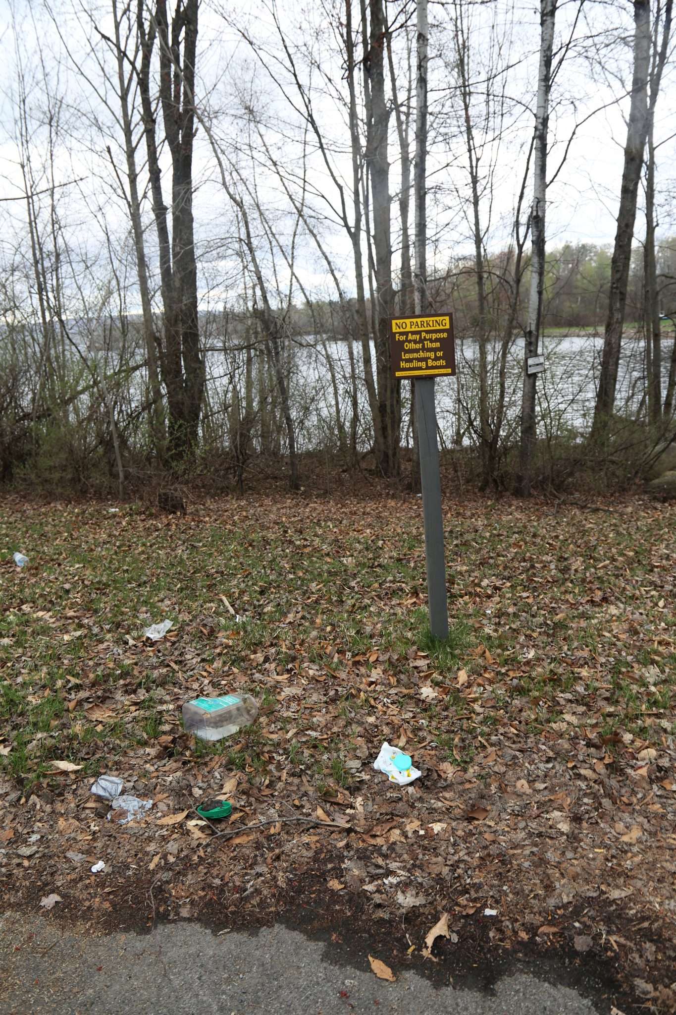 Trash is scattered under a sign for no parking at the Broadalbin Boat Launch.