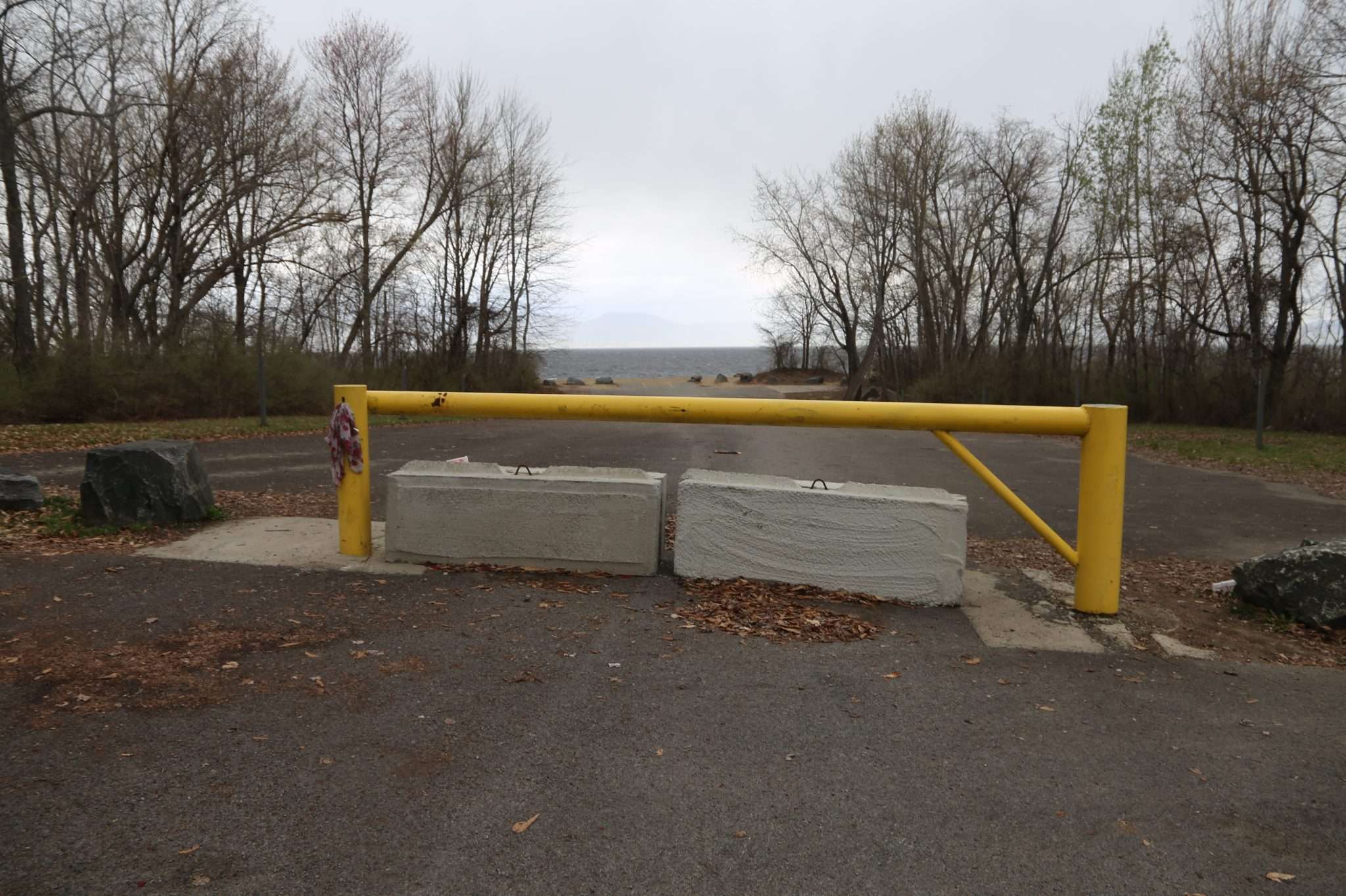 Concrete barriers and a yellow gate sit in the middle of a parking lot once open to the Broadalbin beach.