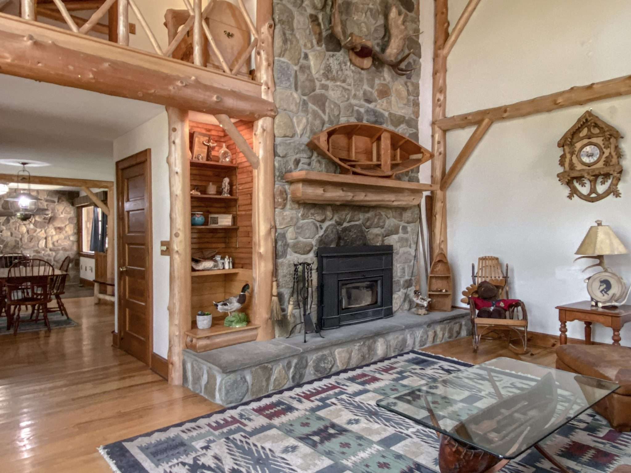 The interior of one of the buildings on the Crossett Lake property includes a stone fireplace, a wooden canoe hung on a stone wall, wood trim and wood furnishings.