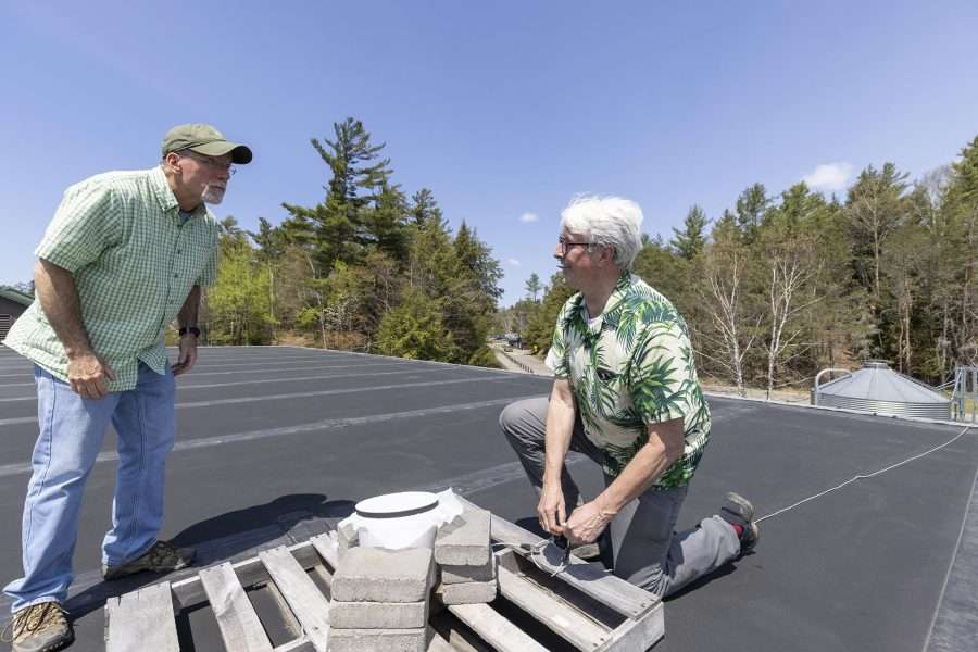 Adjunct professor Brian McAllister looks on as ornithologist Bill Evans, right, sets up a microphone on the roof of the science building at Paul Smith's College to capture bird call notes during nightime bird migrations. Photo by Mike Lynch
