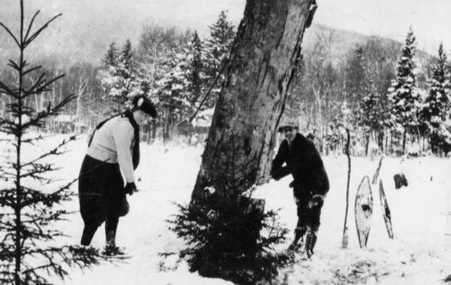 black and white image of couple cutting down a tree