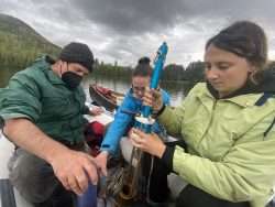 A group of researchers take samples of a lake in the Adirondacks during a cloudy day.