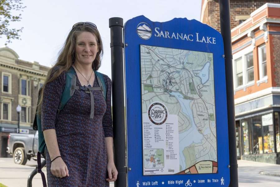 woman next to saranac lake sign
