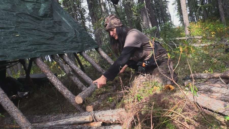 woman building primitive shelter in the woods