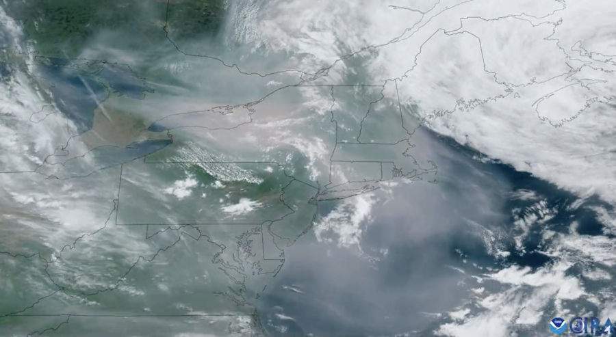 A blue, green and gray satellite image shows smoke blowing down from Canada.