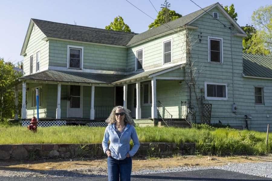 woman in front of old green house