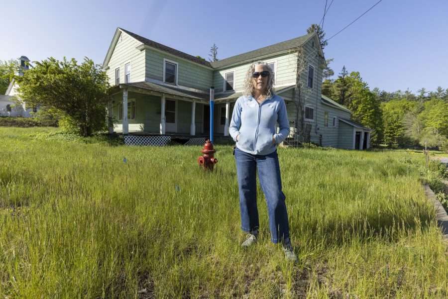 woman in field with old house in the background
