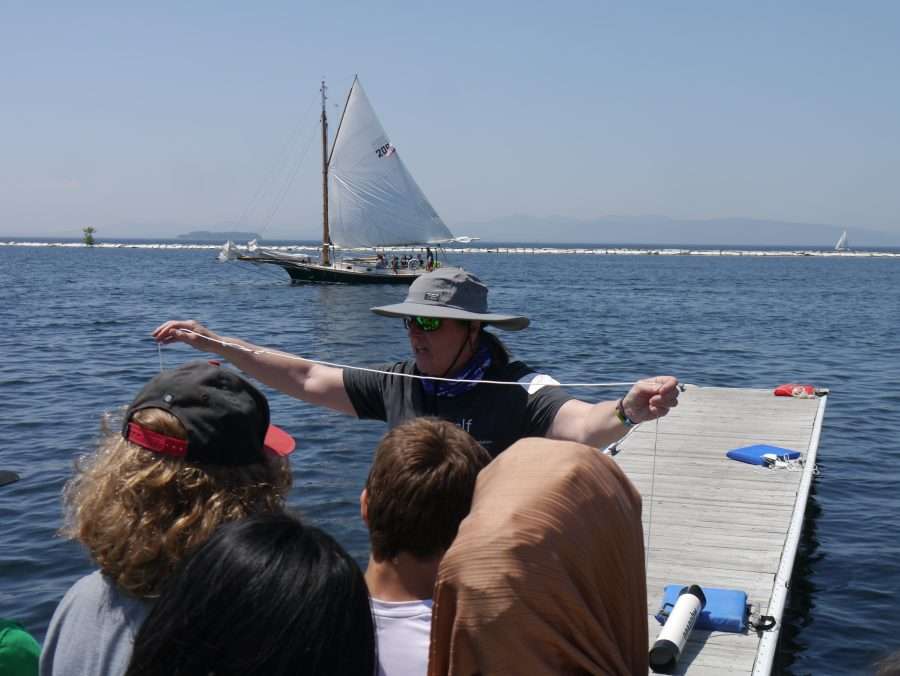 people on a dock with a sailboat in the background