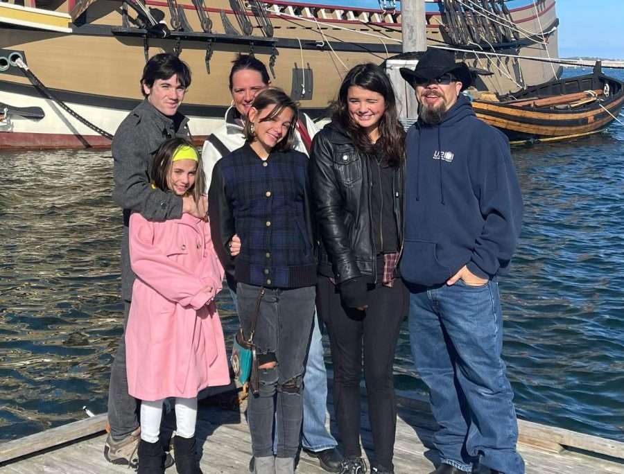 family in front of water and a boat in the background