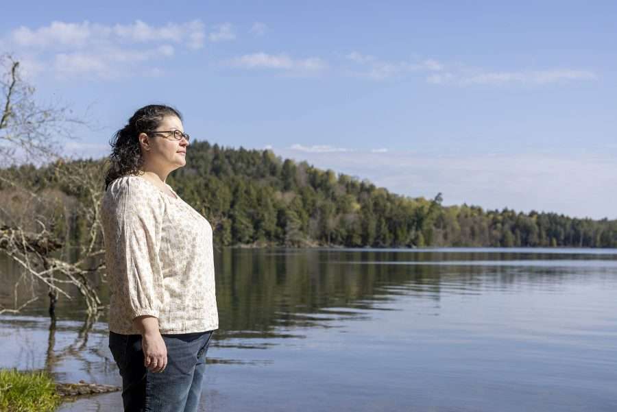 Aurora Pfaff, a Saranac Lake writer who is part Mohawk, stands on the shoreline of LIttle Clear Pond in the northern Adirondacks. 