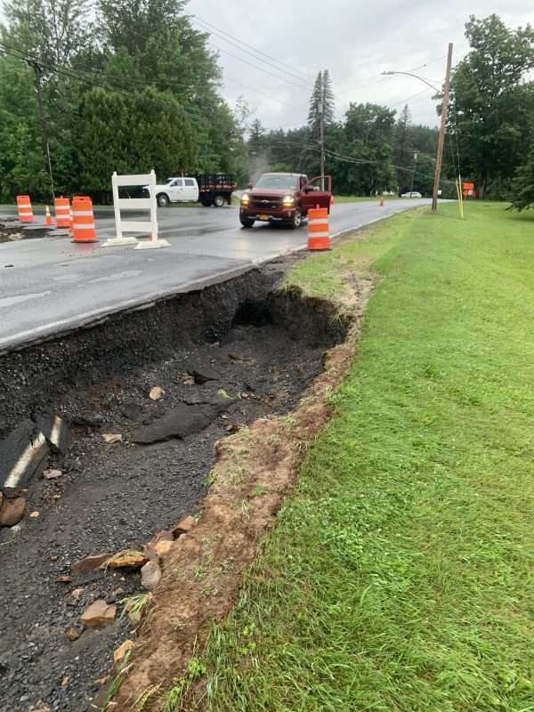 Dirt washed out from under a road during major rainfall, causing flooding concerns.