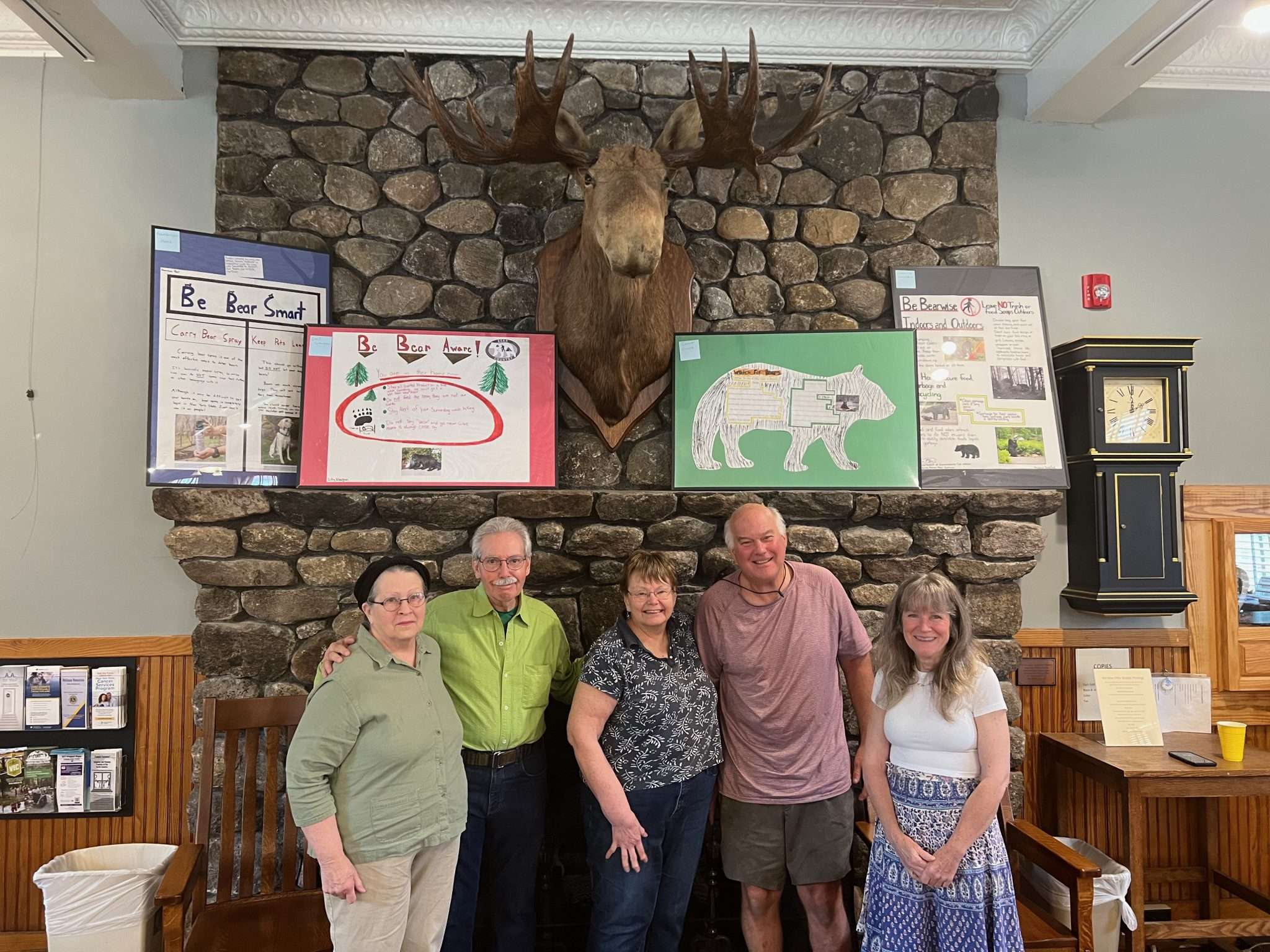 Committee members and visitors gather under the new "Protect Our Bears" posters now displayed in the Long Lake Public Library until August 18. Visitors talked bear safety and shared their own bear stories over cookies and coffee. Photo by Jak Krouse.
