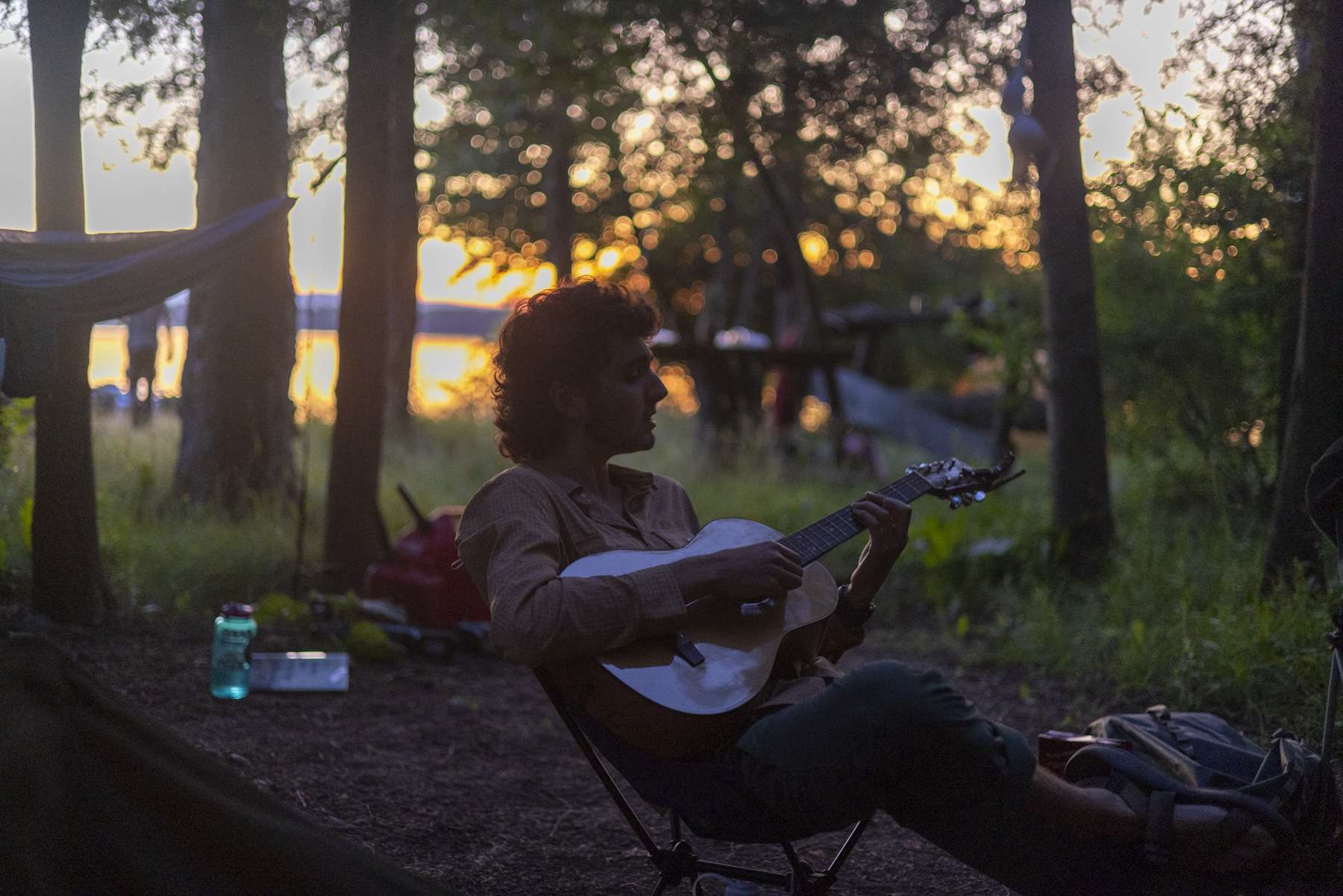 Northern Forest Canoe Trail intern Jonah Yaffe plays guitar at sunset. 