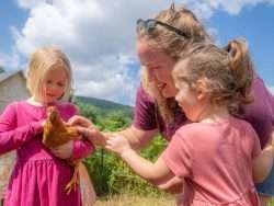 two young girls and a woman. One of the girls is holding a chicken