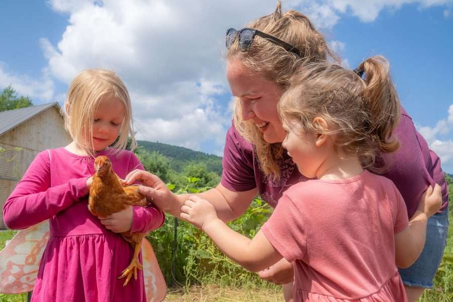 two young girls and a woman. One of the girls is holding a chicken