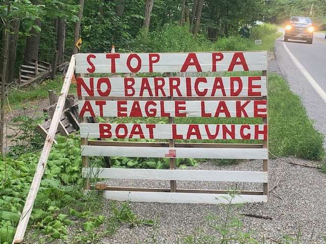 A sign says "Stop APA no barricade at Eagle Lake boat launch"