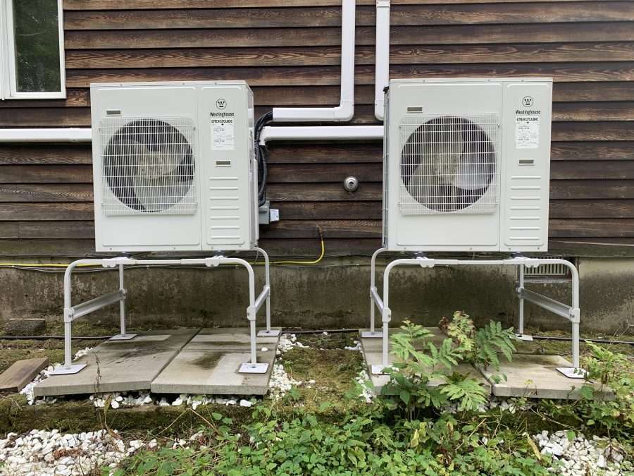 Two heat pumps installed on the side of a house.