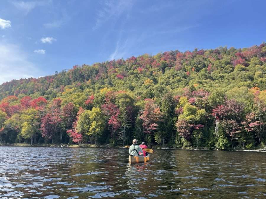 fall colors by a lake with people paddling