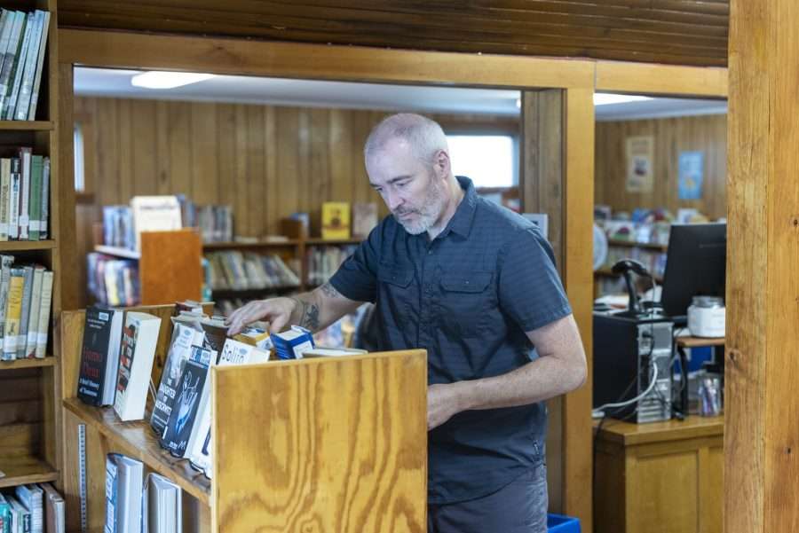Keene Library Director Aaron Miller puts a book one the shelf during his facility's reopening in July. Photo by Mike Lynch