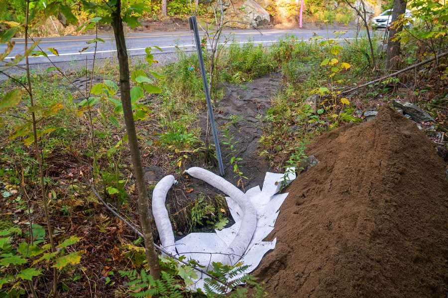 Hazmat crews used sand barriers and booms to contain the spill of truck coat, similar to driveway sealant, from reaching the North Fork of the Bouquet River, which is down an embankment north of the crash site.


