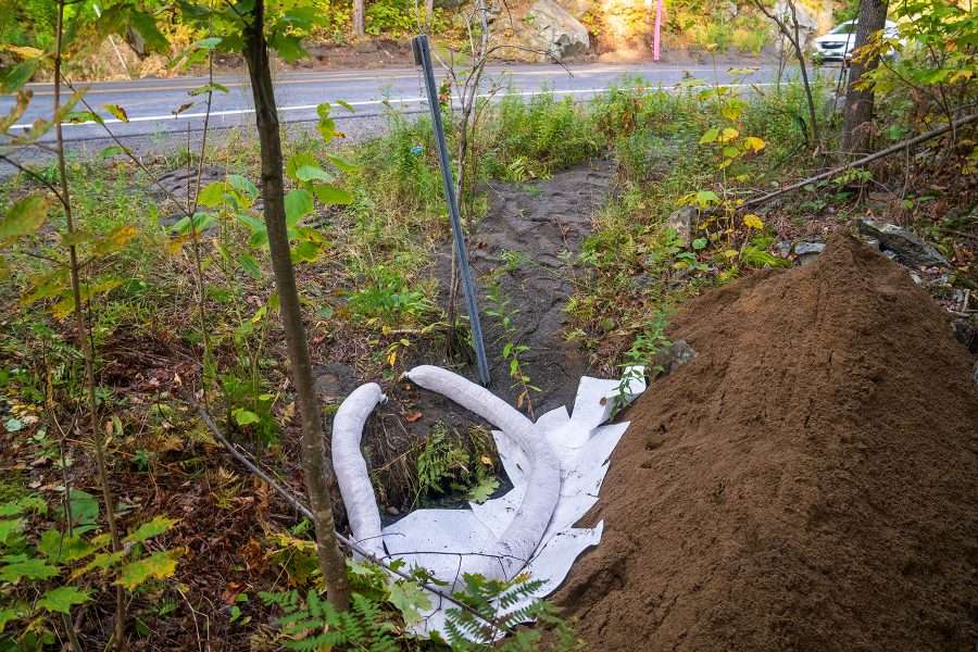 Hazmat crews used sand barriers and booms to contain the spill of truck coat, similar to driveway sealant, from reaching the North Fork of the Bouquet River, which is down an embankment north of the crash site.