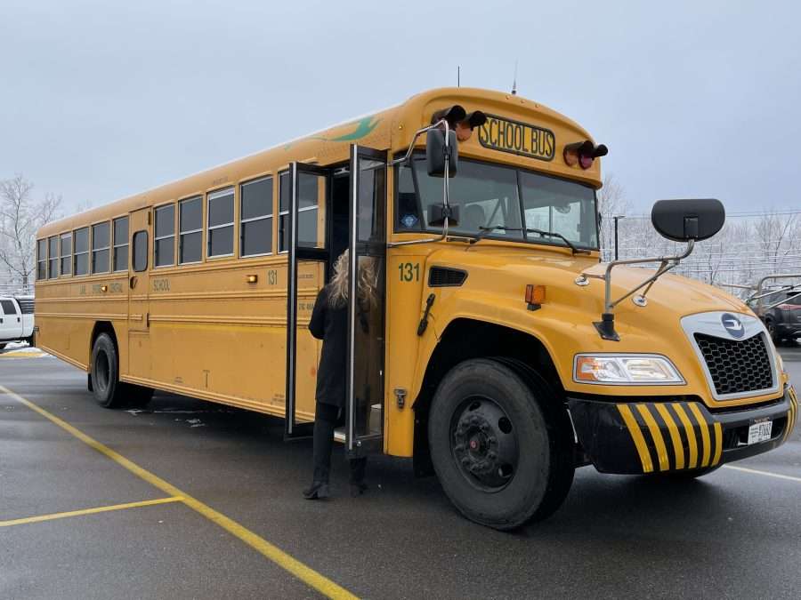 An electric school bus in a parking lot in the winter.