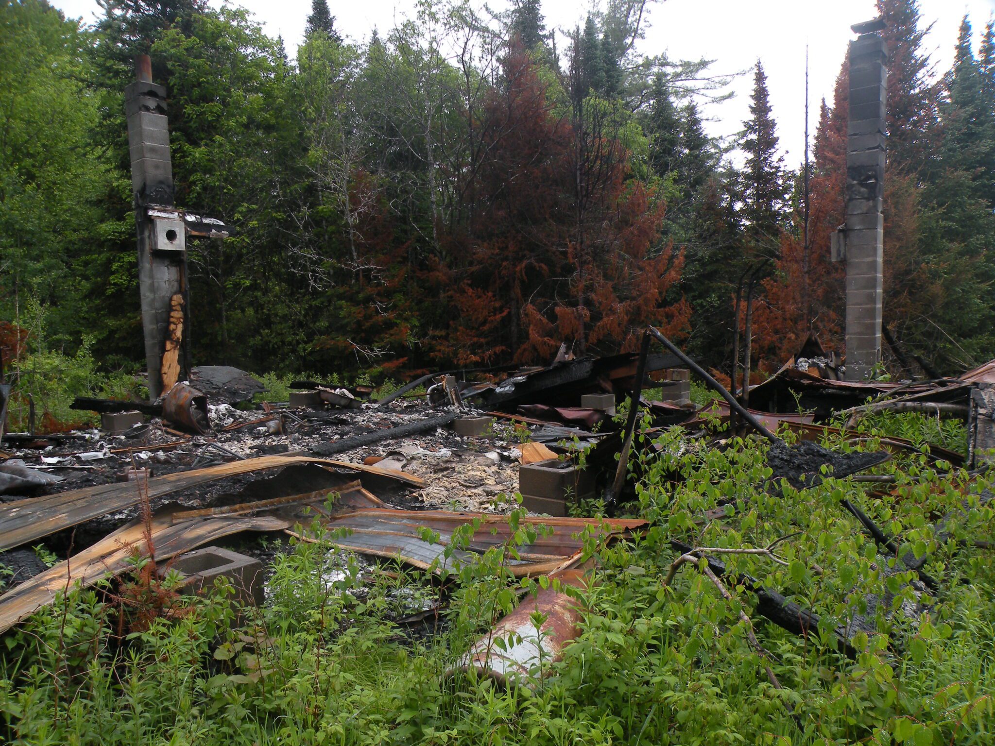 The burnt remnants of a non-conforming structure in wilderness near Little Moose Lake in 2023.