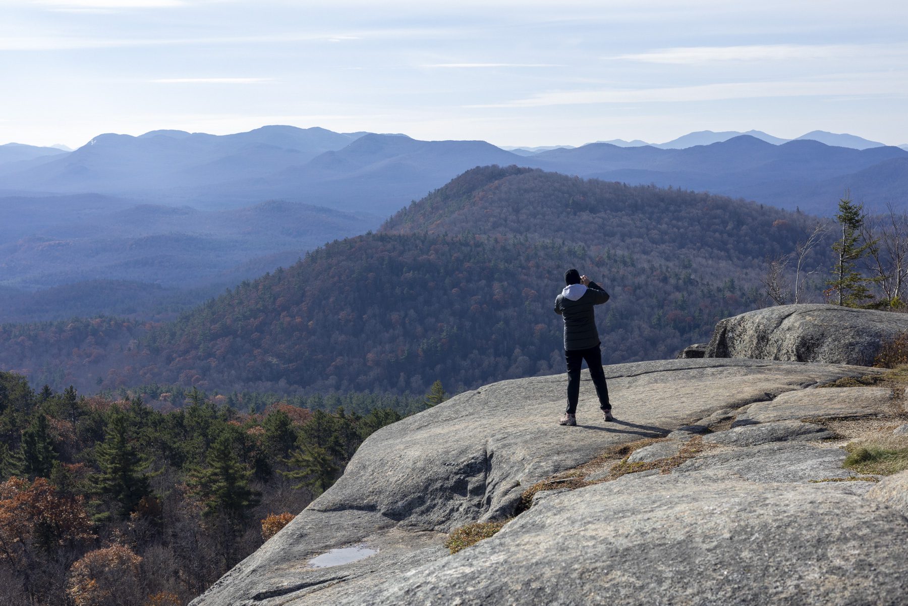 A hiker takes a photo from atop Poke-O-Moonshine Mountain. Photo by Mike Lynch