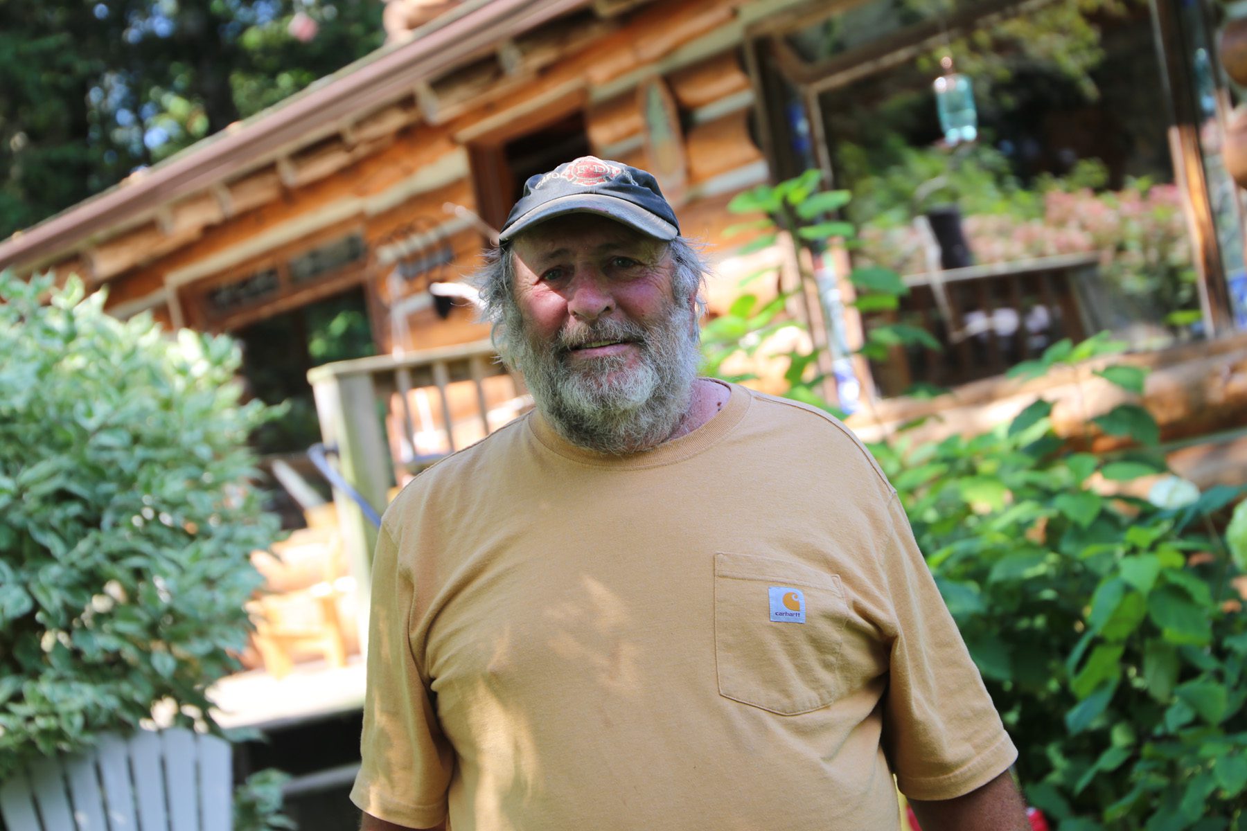 John Houghton stands in front of his off-grid home