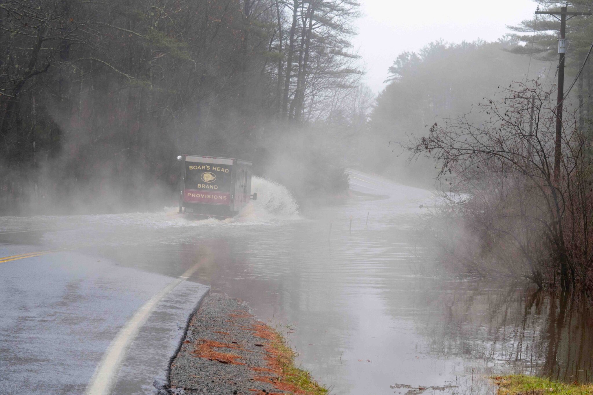a truck drives through water flooding a road. Recent rains causing road closures