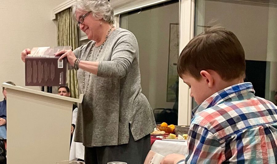 Author Amy Godine reads from her new book “The Black Woods” as a young reader follows along.