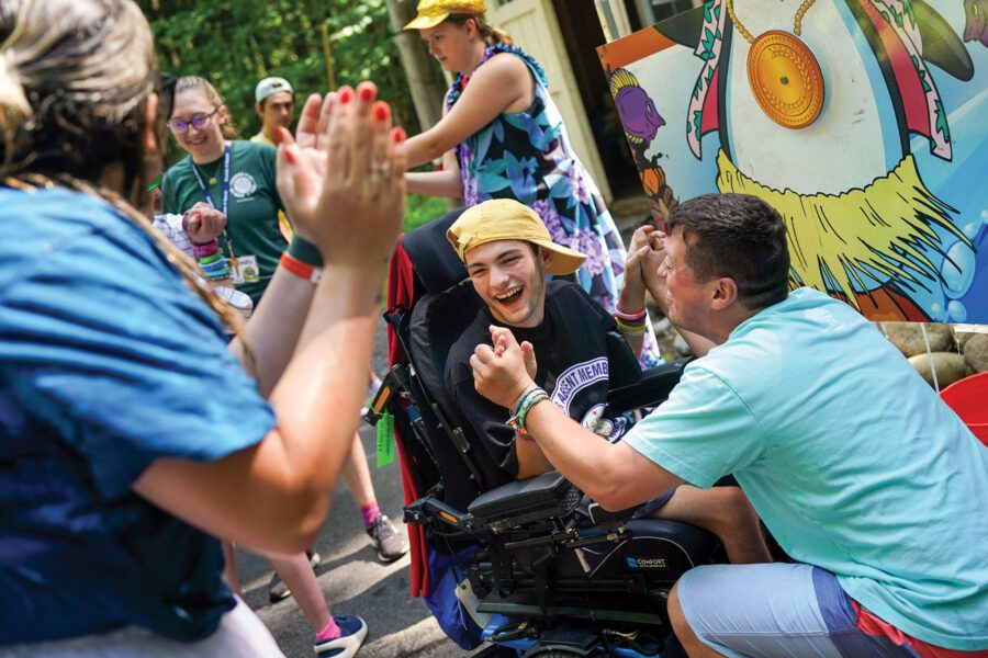 kid in wheelchair surrounded by people at Double H Ranch
