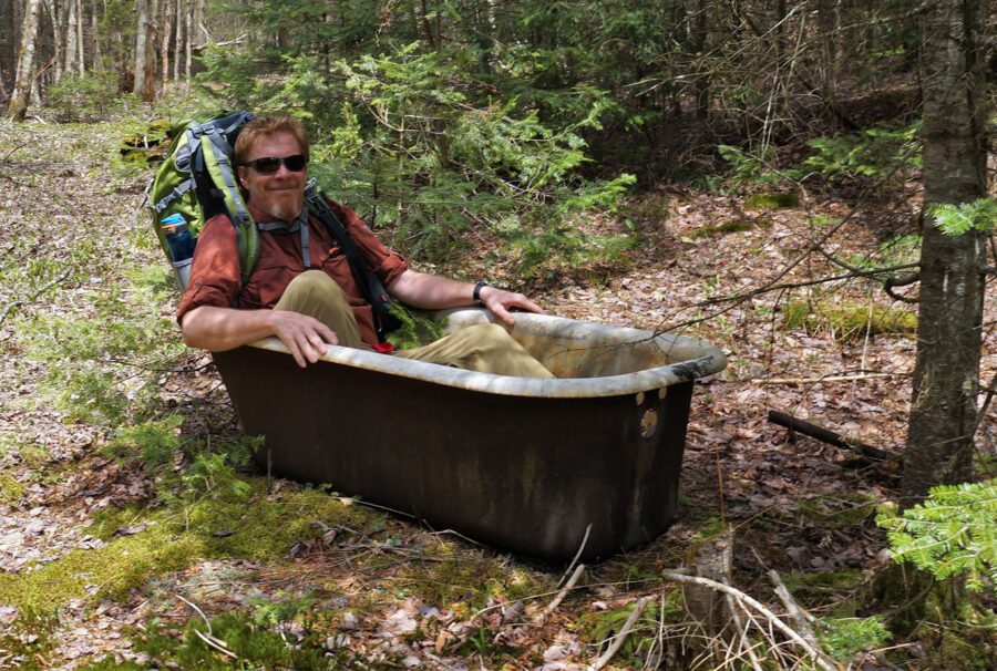 man in an old bathtub in the woods