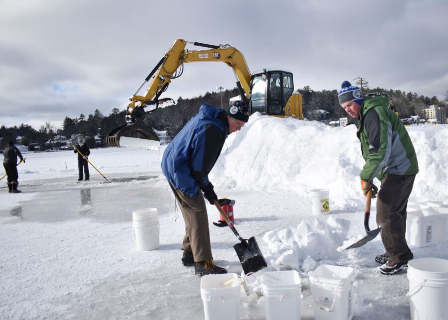 two men with shovels, putting snow in white buckets