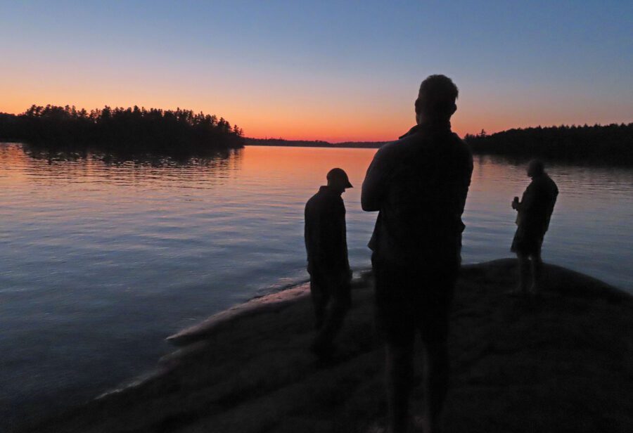 three men watching a sunset