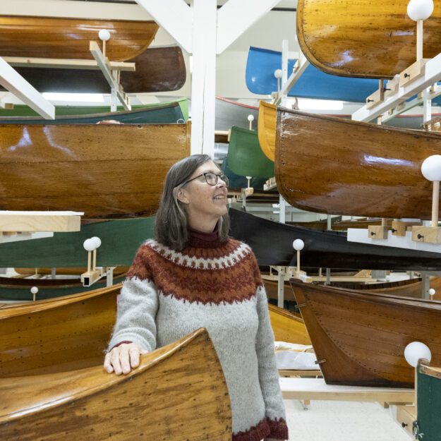 woman standing among antique canoes