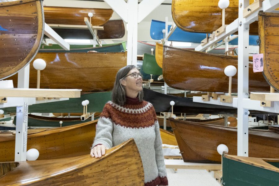 woman standing among antique canoes
