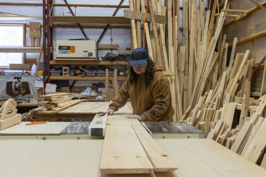 man cutting a board on a modular home he's making