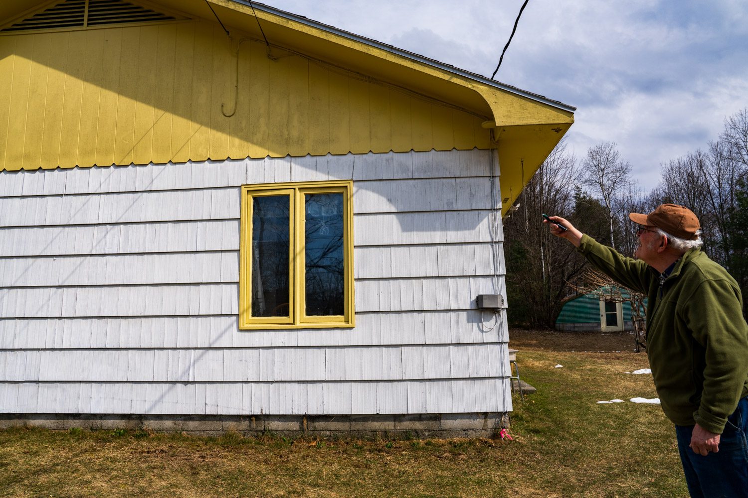 Greg Furness using a laser pointer showing black whiskey fungus on his house in Moriah