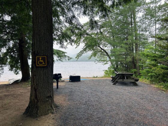 A beach area with a wheelchair-accessible picnic table, grill, and ramp.