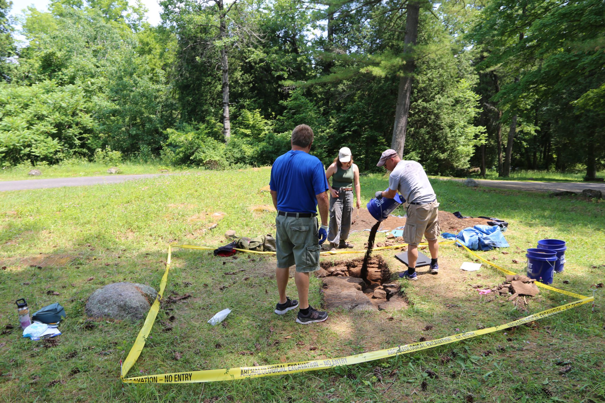 People fill in an archaeological test pit 