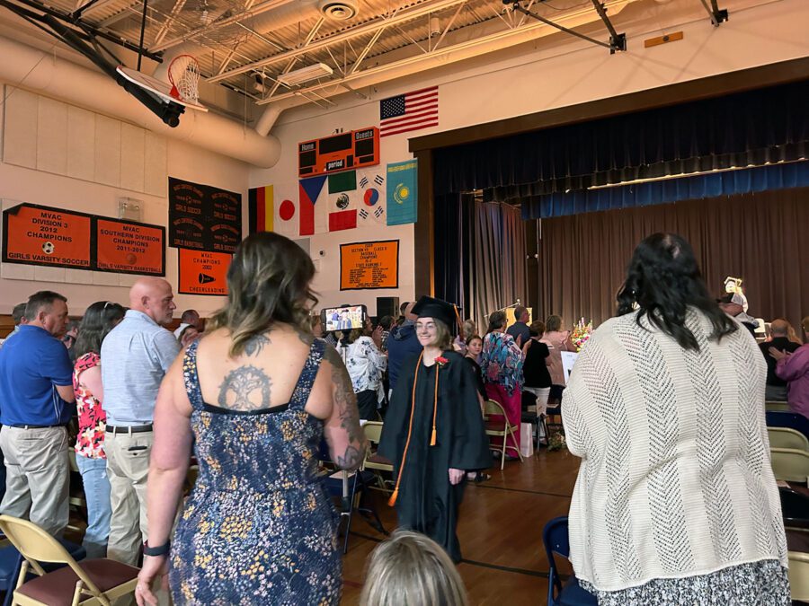 Graduate walks through a crowd.