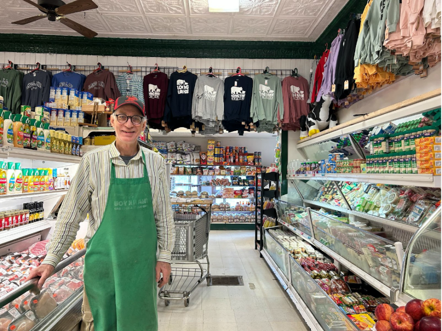 man in green apron in a small grocery store