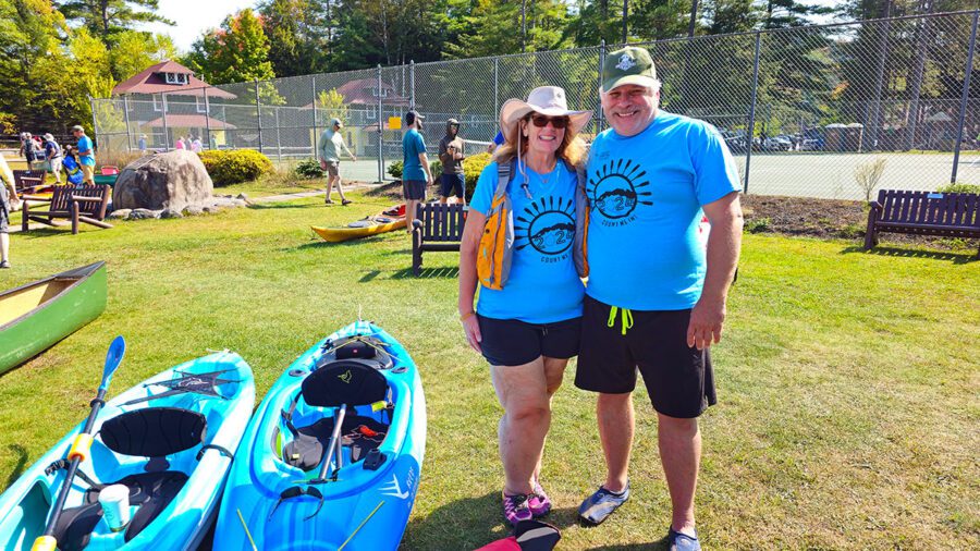 couple in blue, next to blue kayaks
