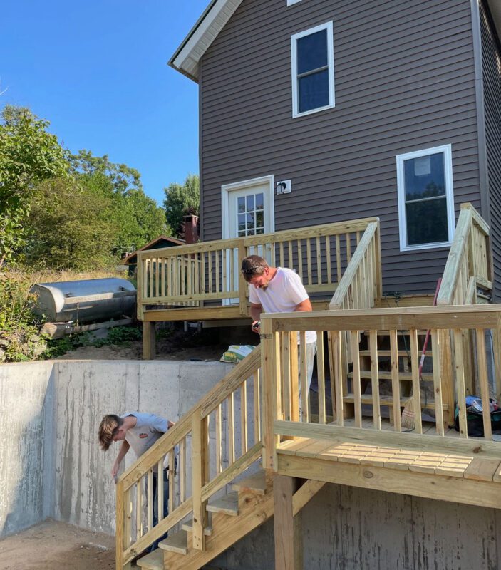 two men working on a gray house