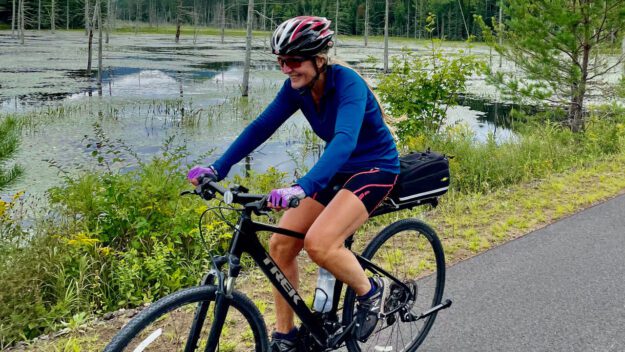A woman riding a bike on the Placid-to-Saranac segment of the Adirondack Rail Trail