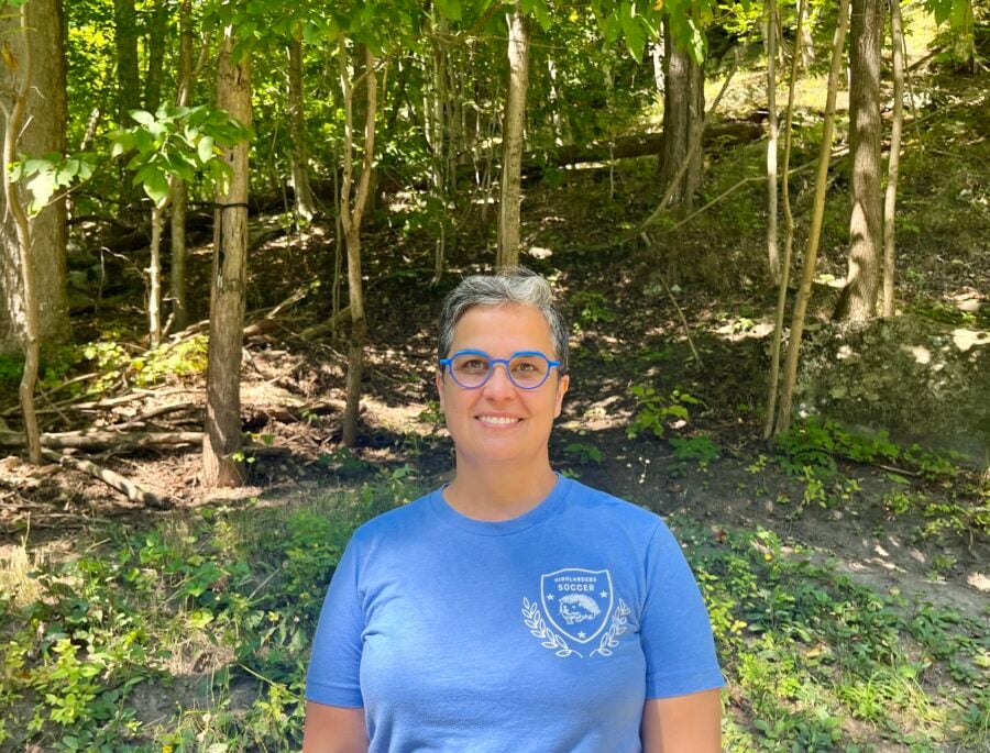 Sunita Halasz stands near trees outside in the Adirondacks