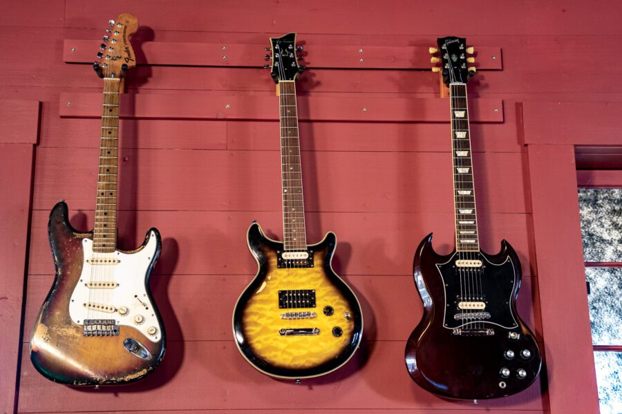 three classic guitars hanging on a red wall at 22 Pawn in Essex NY