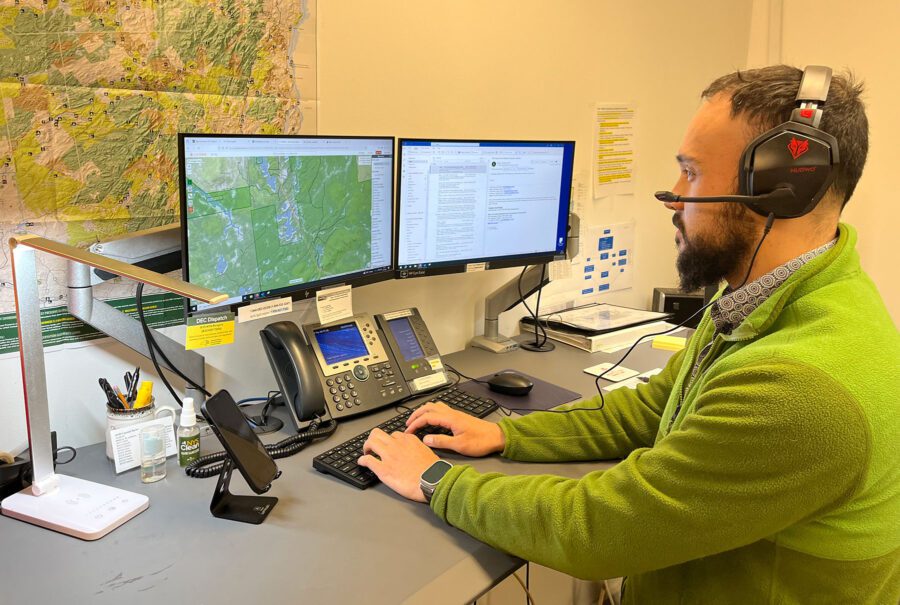 a man in green sweater in front of monitors