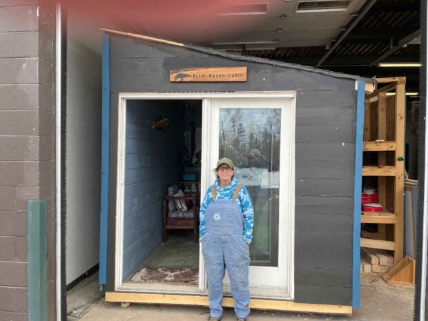 Deb Naybor stands outside of the Blue Raven Cabin. The tiny home is being built by Paul Smith's College students as a capstone project. Photo by Rick Karlin